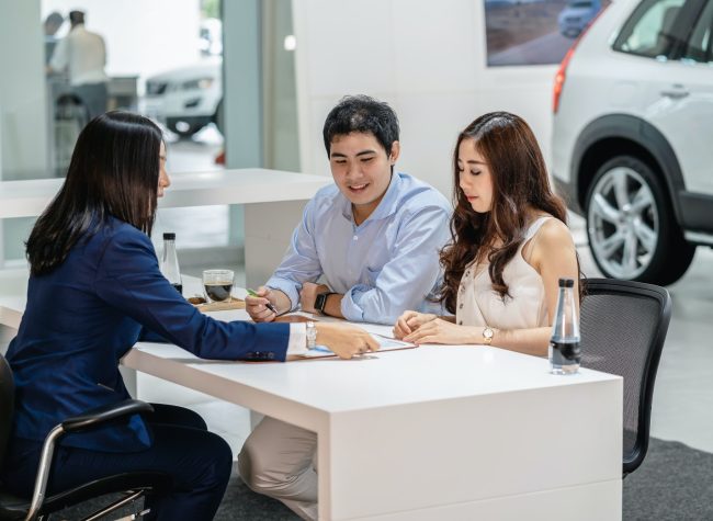 Asian Saleswoman explaining sales contract to couple customer before decision