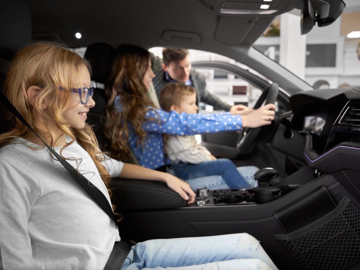 Friendly family testing and observing car in auto salon