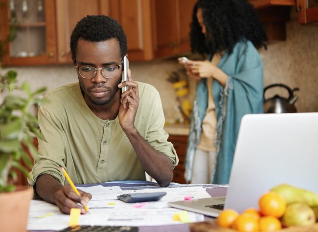 Serious African man having phone conversation with bank asking to extend loan term for paying out mo