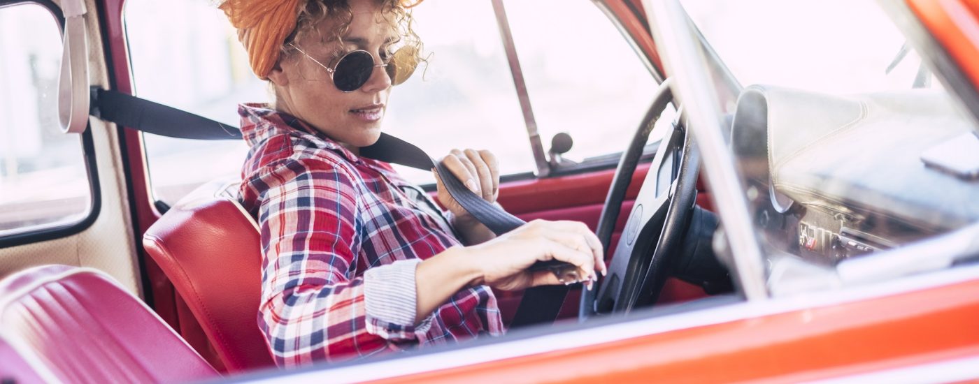 Woman holding using safety belt inside the car viewed from outside - concept of insurance